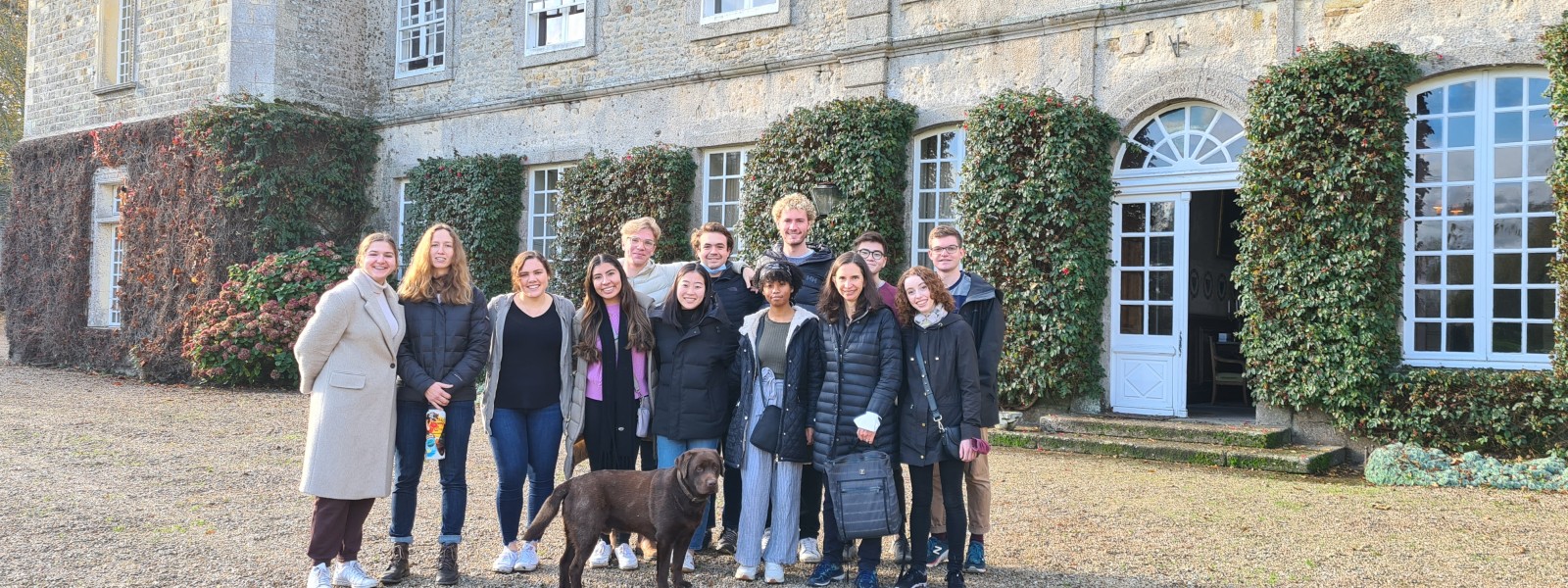 The group stands together in front of the château. A resident dog joined them for the photo.