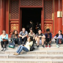 Eight students sit together on the steps of the temple.