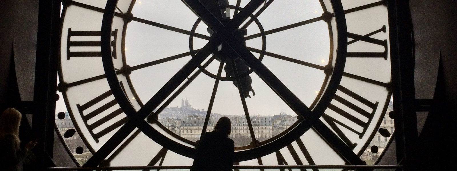 A person looks out at Paris through the Musée d’Orsay clock window