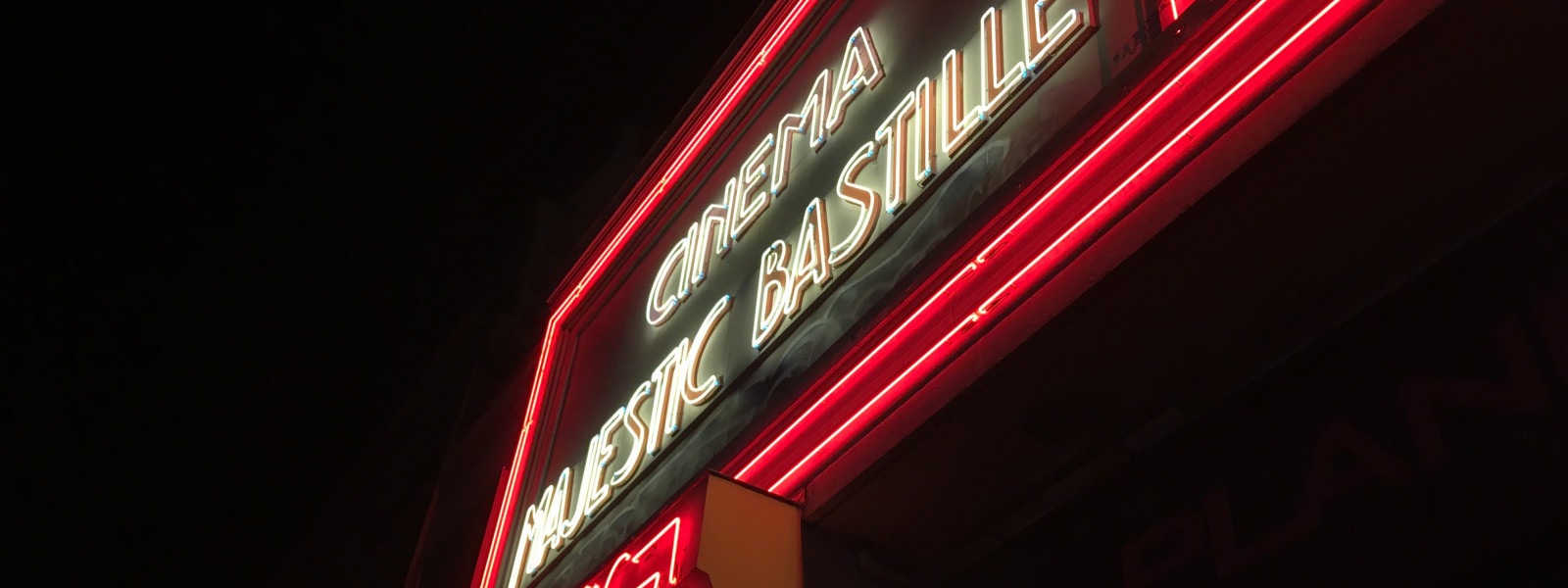 A neon sign for Cinema Majestic Bastille at night