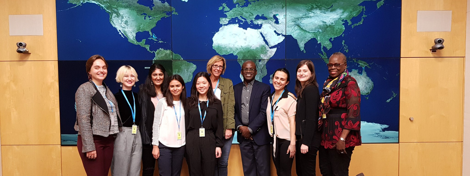 The group poses for a photo in front of a world map at the World Health Organization in Geneva.