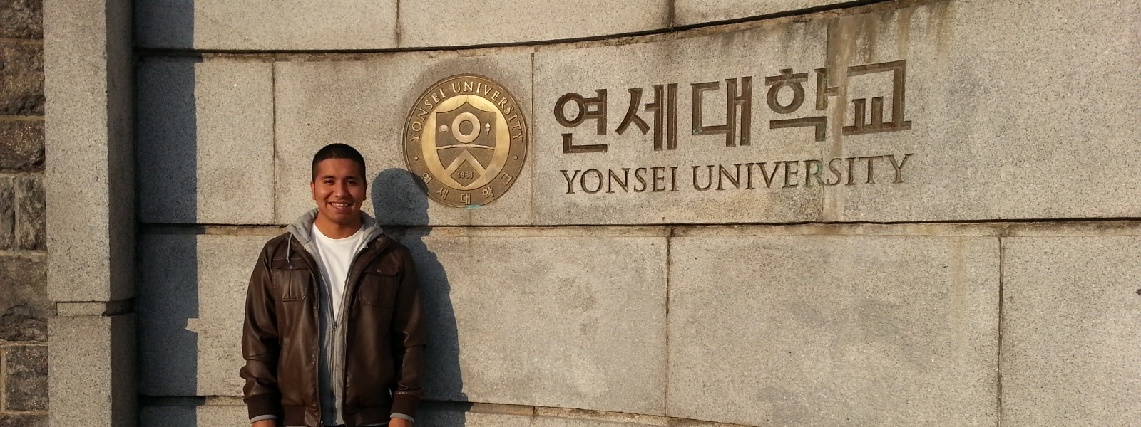 A student poses in front of a Yonsei University sign.
