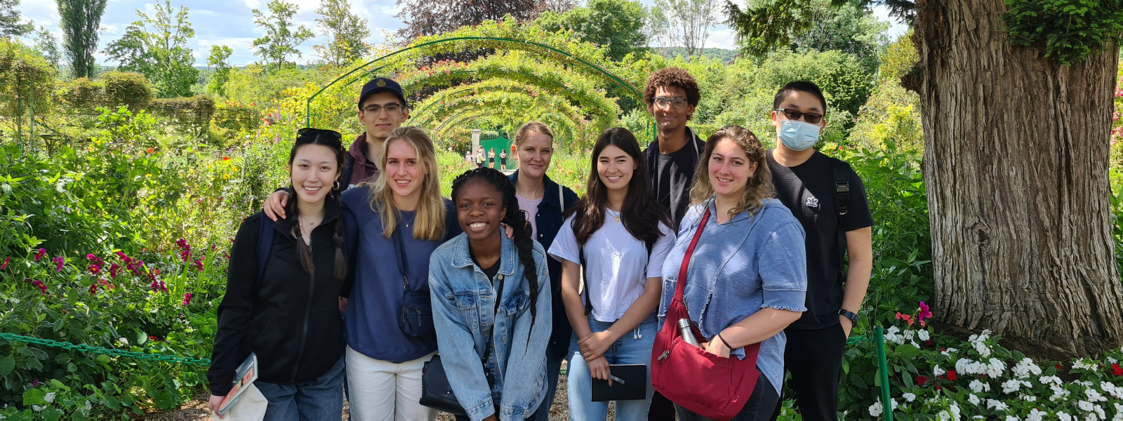 Nine students pose for a photo in the garden.