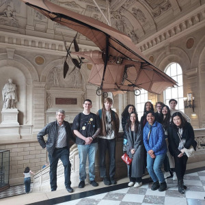 Professor and students pose for a photo inside a museum