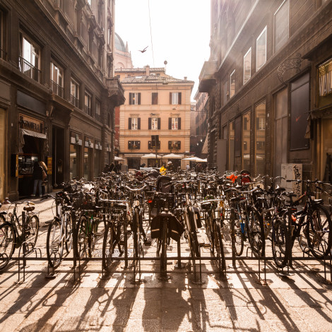 In the center of Bologna, rows of parked bicycles gleam in the sun.