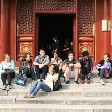 Eight students sit together on the steps of the temple.